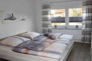 A bedroom with a bed, a window with curtains, and two wall-mounted pictures. - Rudi's orchard "Este" (Jork)