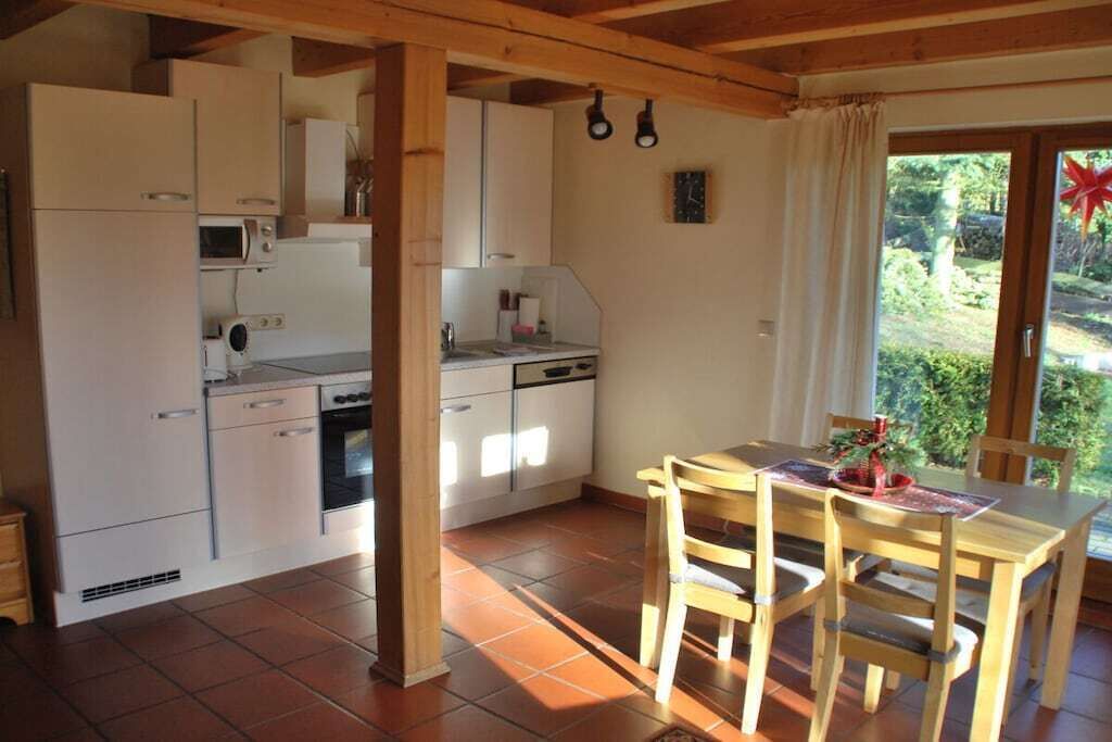 Cocina compacta con comedor, vigas de madera y vistas al exterior.