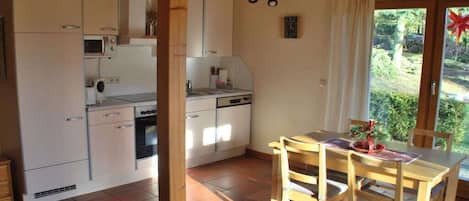 Cocina compacta con comedor, vigas de madera y vistas al exterior.