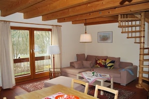A cozy living room with a wooden ceiling, a sofa, a table, and a staircase. - "East" in the holiday home "Keilbergblick" (Kurort Oberwiesenthal)