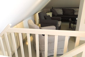 A staircase leading to a living area with a sofa, armchairs, and a small table. - Holiday home with 2 bedrooms (Krummhörn)