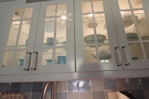 A kitchen with white cabinets, glass doors, and a tiled backsplash. - Holiday home with 2 bedrooms (Krummhörn)