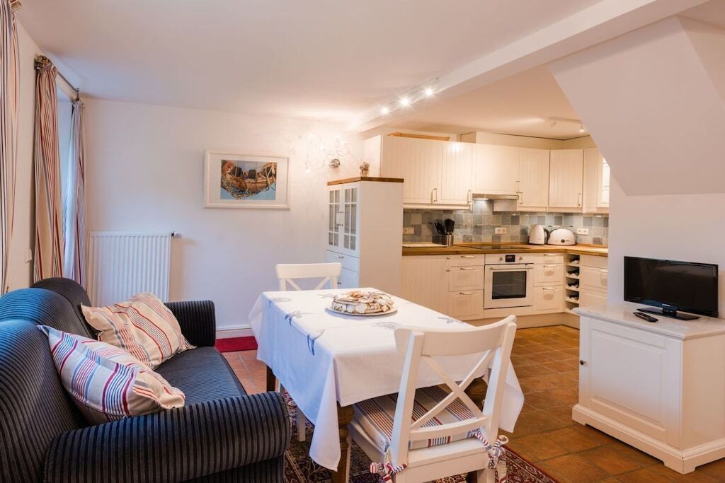 Un espace de vie compact comprenant un coin repas, une kitchenette et un téléviseur posé sur un meuble.