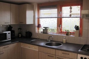 Une cuisine équipée d’un évier à deux bacs, d’un four à micro-ondes et de placards.