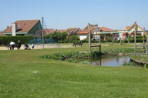 Une aire de jeux avec des structures d’escalade et un petit étang.