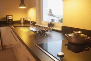 Une cuisine moderne équipée d’une plaque de cuisson, d’une bouilloire et d’une machine à café.