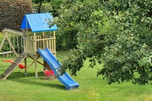 Eine Holzspielanlage mit einer blauen Rutsche und einem Kletterbereich.