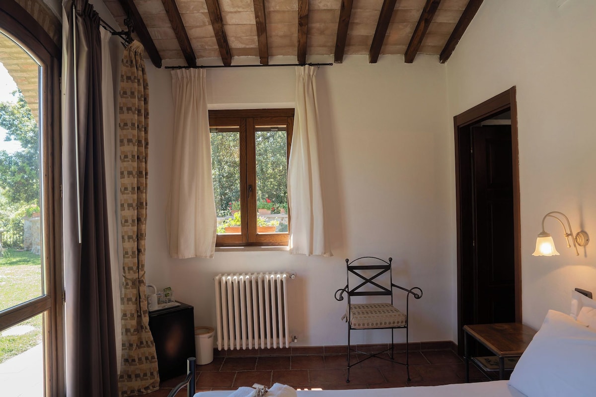 A room with a bed, a radiator, a chair, a window with curtains, and a door.