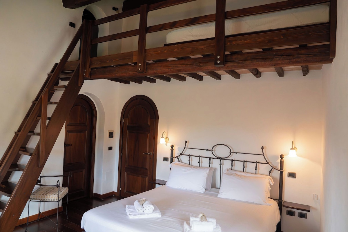 A bedroom with a bed, a wooden staircase, and two arched doors.