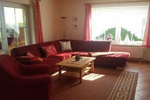Ein Wohnzimmer mit einem roten Sofa, einem Holztisch und einem gemusterten Teppich.