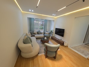 A modern living room with a sofa set, a coffee table, and a TV mounted on the wall. - Luxury stay in Sheikh Zayed, beside schools, malls (6th October)
