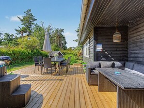 Una terrazza esterna con tavolo e sedie, un barbecue e una lampada a sospensione.