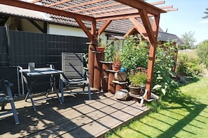 En uteplats med en pergola av trä, ett bord och stolar.