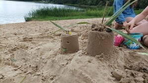 Een zandstrand met twee zandsculpturen en een persoon in de buurt.