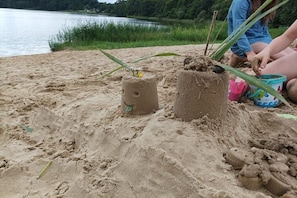 En sandstrand med två sandskulpturer och en person som sitter i närheten.