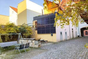 Ein Innenhof mit einer Steinsitzbank, einer Schaukel und einer Solaranlage.
