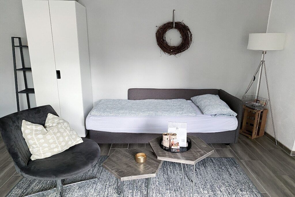 Ein modernes Schlafzimmer mit Bett, Stuhl, Nachttisch und Lampe.