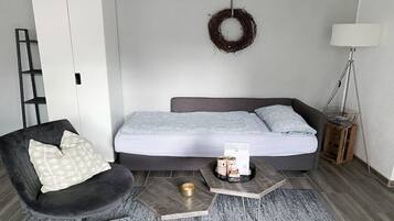 Ein modernes Schlafzimmer mit Bett, Stuhl, Nachttisch und Lampe.