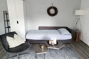 Ein modernes Schlafzimmer mit Bett, Stuhl, Nachttisch und Lampe.
