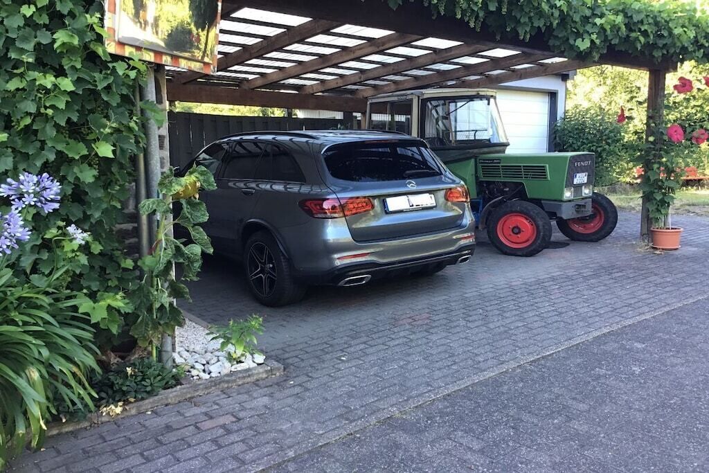 Un vehículo estacionado bajo un techo, con un edificio al fondo.