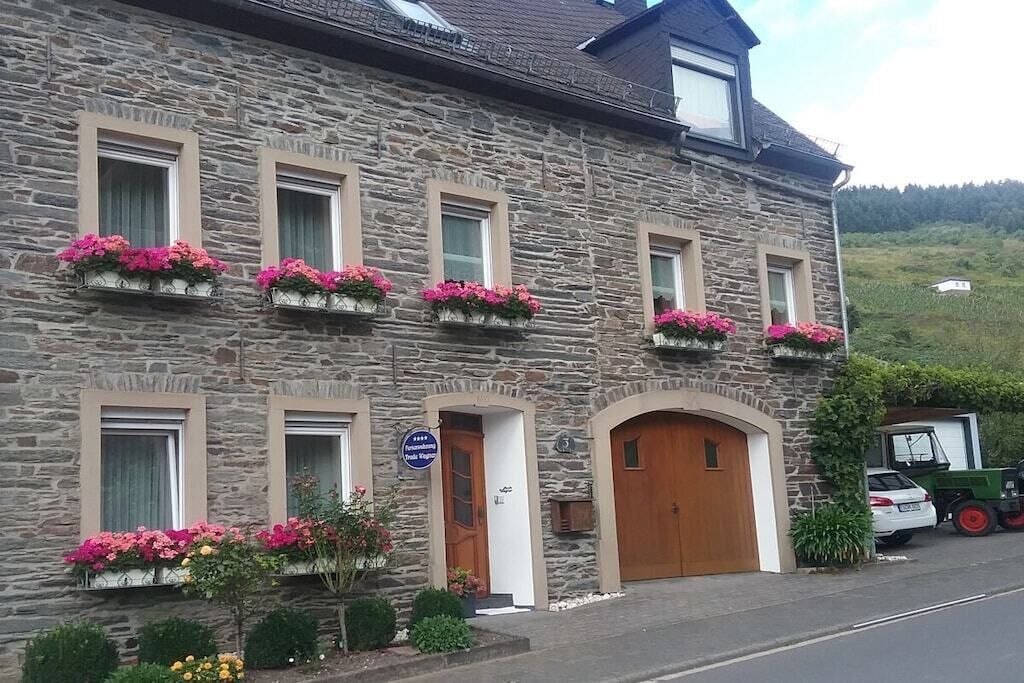Un edificio de piedra con múltiples ventanas, algunas con macetas de flores, una puerta de madera y un letrero que indica un restaurante.