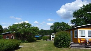 A row of mobile homes with a grassy yard and trees. - in the holiday village "Boeker Mühle" (Boeker Mühle)