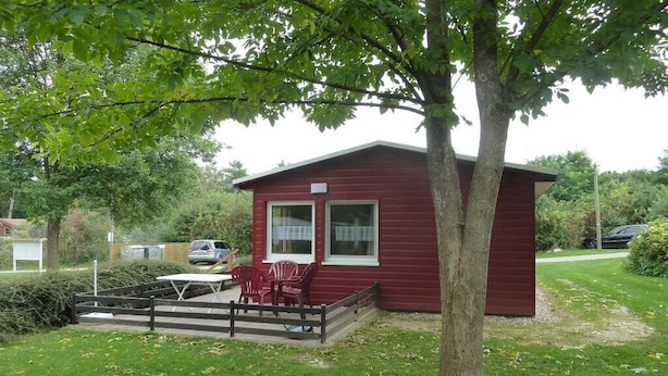 A red cabin with a deck, a table, and chairs. - in the holiday village "Boeker Mühle" (Boeker Mühle)