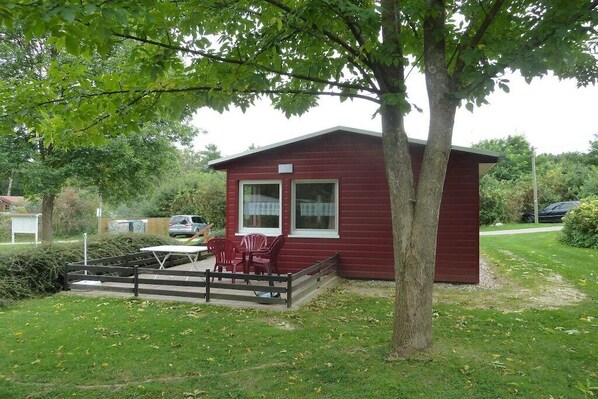 A red cabin with a deck, a table, and chairs. - in the holiday village "Boeker Mühle" (Boeker Mühle)