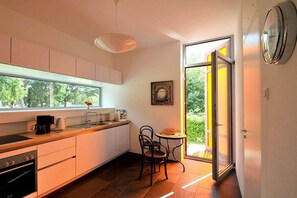Eine moderne Küche mit Essbereich, einer Kaffeemaschine und Blick durch eine Glastür.