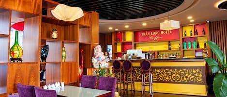A hotel lobby with a bar area, purple seating, and a decorative statue.