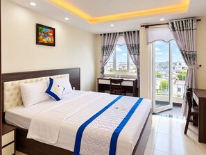 A hotel room with a bed, a desk, and a view of the city. - Tran Long Hotel (Binh Duong)