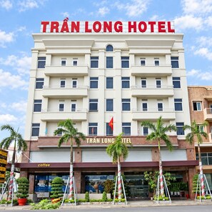 Un hotel de varios pisos con un cartel llamativo que dice 'TRÁN LONG HOTEL'.