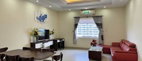 A modern living room with a dining area, a sofa, a TV, and a window with curtains.