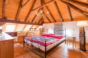 Ein Schlafzimmer mit Holzboden, einem Bett mit roter und blauer Bettdecke, einem Schreibtisch und einem Stuhl.