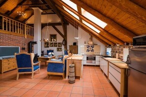 A rustic kitchen with a wooden ceiling, a brick wall, and a tiled floor. - Holiday home with 2 bedrooms (Südbrookmerland)