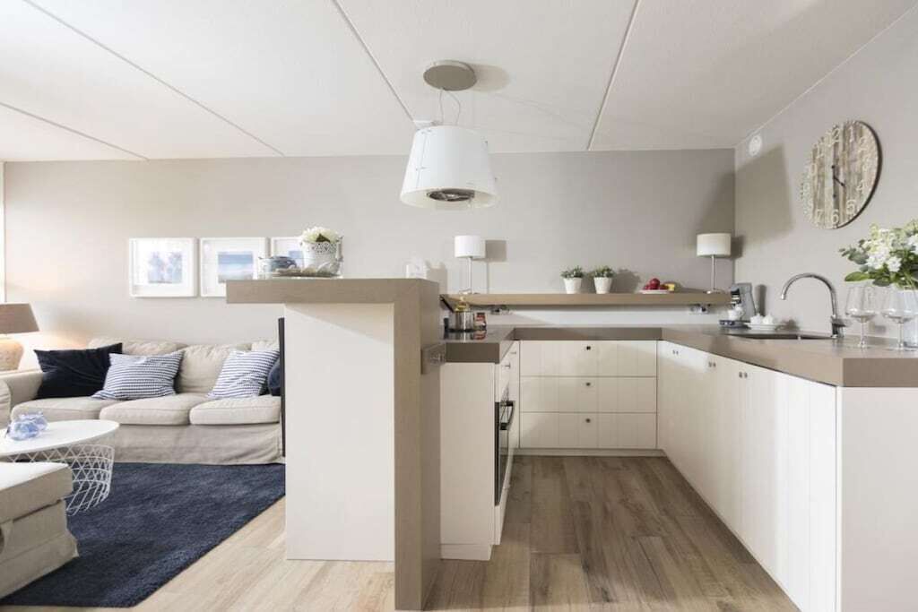 Een moderne keuken met witte kasten, een houten aanrecht en een hangende lamp.