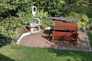 Een terras met een houten bank en een ronde vuurkuil.