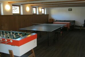 A room with a foosball table, a ping pong table, and a sofa. - Holiday apartment with 2 bedrooms (Burgberg)