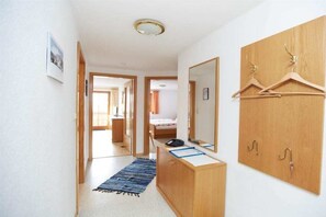 A hotel room with a wooden wardrobe, a mirror, a desk with a telephone, and a hanging coat rack. - Holiday apartment with 2 bedrooms (Burgberg)