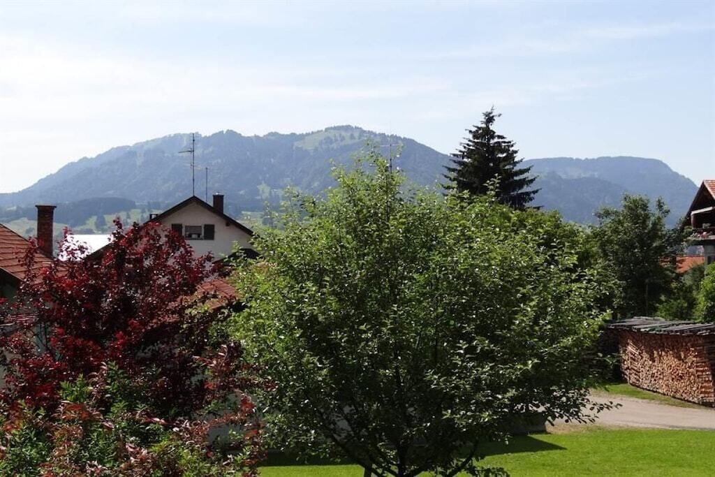 A residential area with houses, a tree, and mountains in the background.