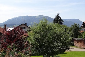 Ein Wohngebiet mit Häusern, einem Baum und Bergen im Hintergrund.