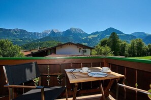 A wooden deck with a table set for two, overlooking a mountain landscape. - Alpine view from the Thiele house (Schönau am Königssee)