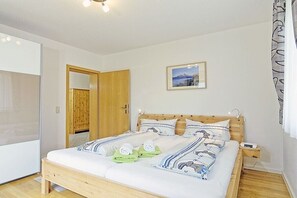 A bedroom with a wooden bed, a nightstand, a wooden wardrobe, and a framed picture on the wall. - Alpine view from the Thiele house (Schönau am Königssee)