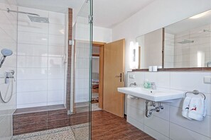 A modern bathroom with a glass-enclosed shower, a white sink, and a large mirror. - Alpine view from the Thiele house (Schönau am Königssee)