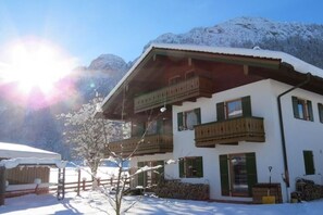 Eine zweistöckige Chalet mit Balkon, umgeben von schneebedeckten Bergen.