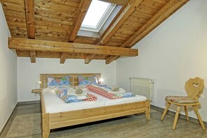 A bedroom with a wooden bed, a skylight, a radiator, and a wooden chair. - Jenner in the Thiele House (Schönau am Königssee)