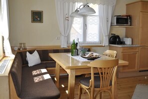 Uma cozinha acolhedora com uma mesa de madeira, um banco e um micro-ondas.