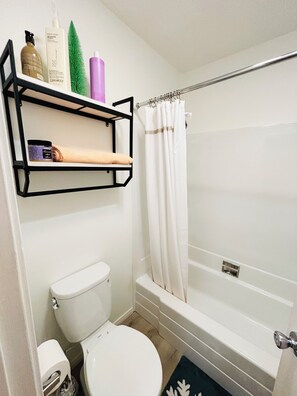 Un baño con inodoro, bañera y cortina de ducha.