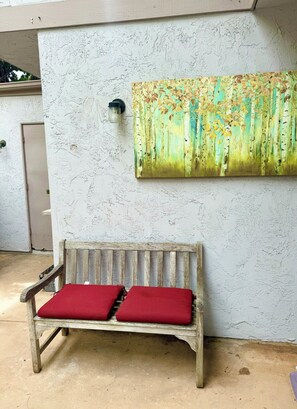 A wooden bench with red cushions against a textured wall, a door, and a wall-mounted light fixture. - Beautiful 2-bedroom townhome in delightful San Diego near the beach (San Diego)