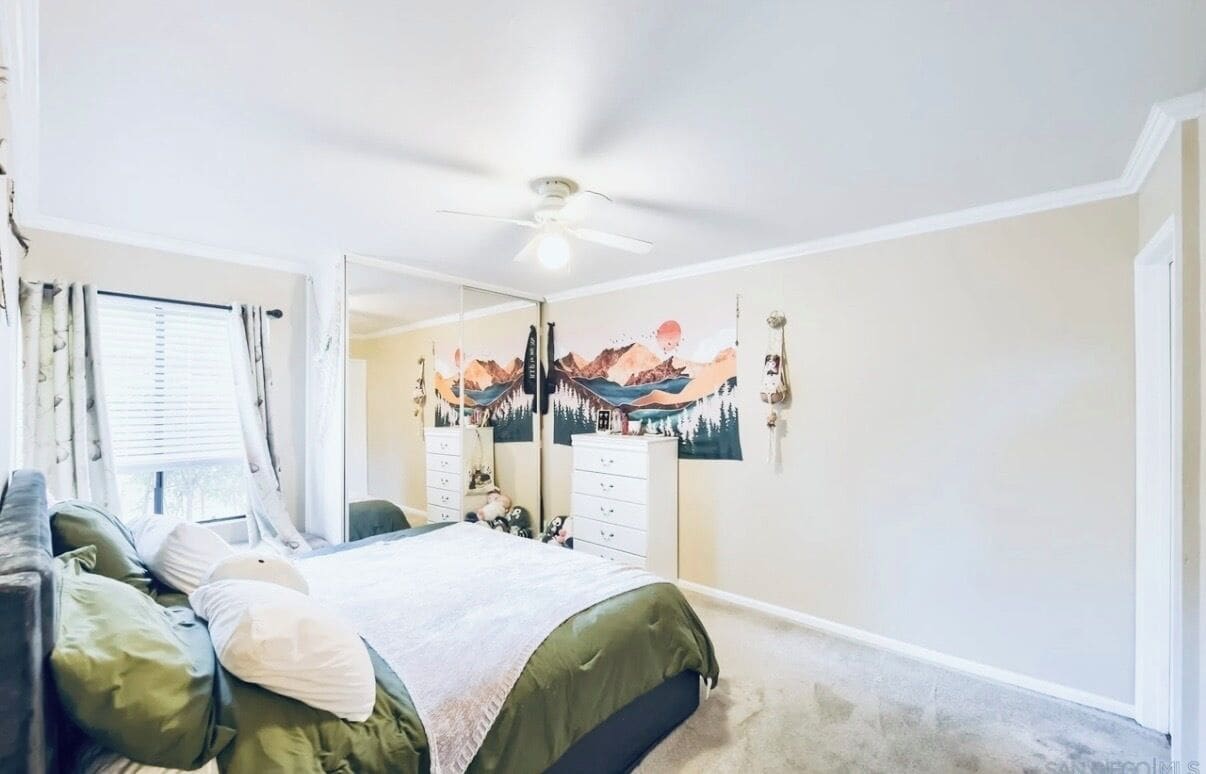 Ein Schlafzimmer mit Bett, Kommode, Spiegel und Deckenventilator.